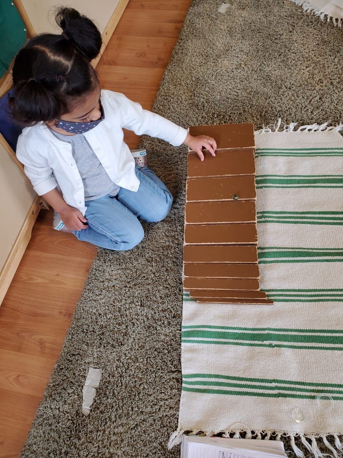 Paoli Campus: A child focused on rolling the marble on the Brown Stairs  from the thickest to thinnest. This activity helps in the refinement of Visual sense.