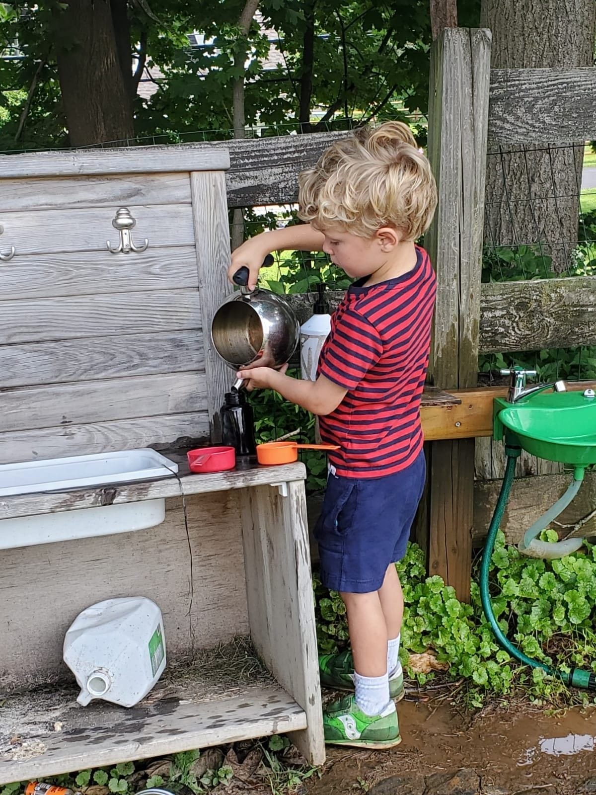 A child working in the mud kitchen during the summer camp at our Paoli Campus.